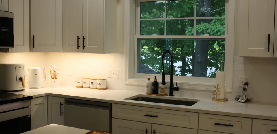 Completed kitchen with cabinets, countertops, sink, lighting, and finish work