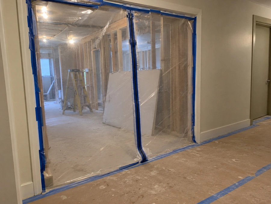 Plastic dust barrier separating a reconstruction work area from an occupied hallway in a multi-unit building